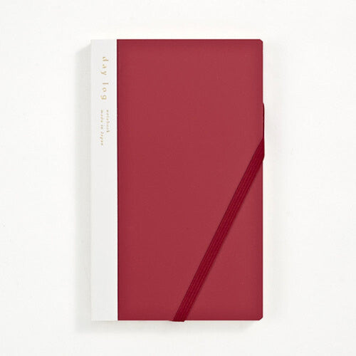 A vertical hardcover notebook with a deep red cover and a white spine band, secured with a matching red elastic closure, shown on a clean white background.