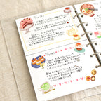 A diary written with Japanese applied with different cake and tea stickers.