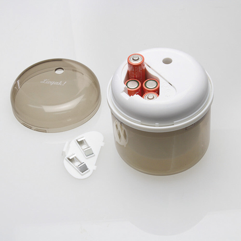 Cylindric electric pencil sharpener in beige with lid opened filled with 4 batteries.