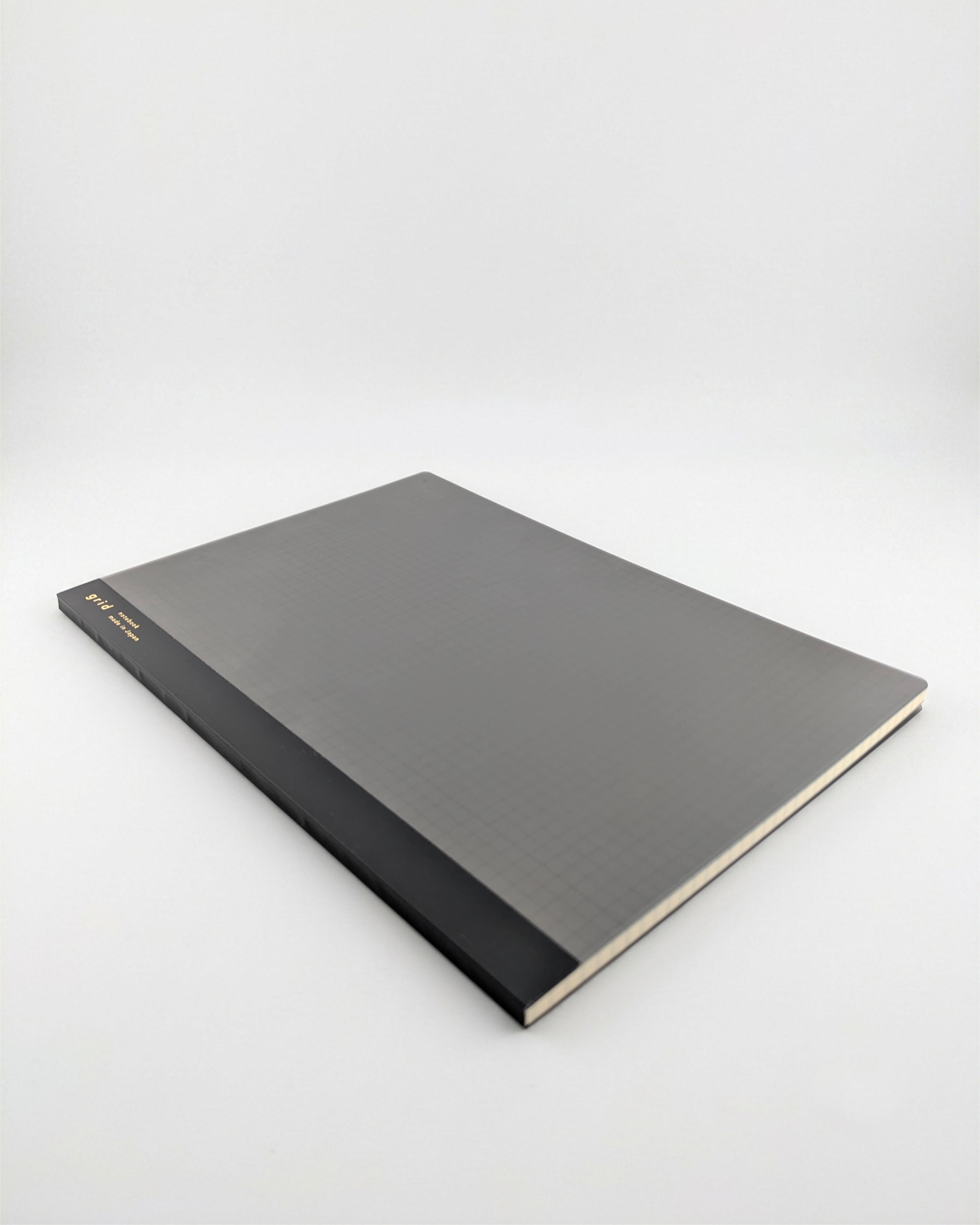 A hardcover notebook or journal with a textured dark gray cover and a black spine, photographed at an angle on a light gray background.