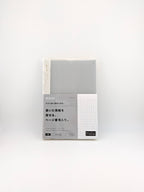 A packaged notebook with a light gray grid cover and a white label section featuring Japanese text, photographed against a plain white background.