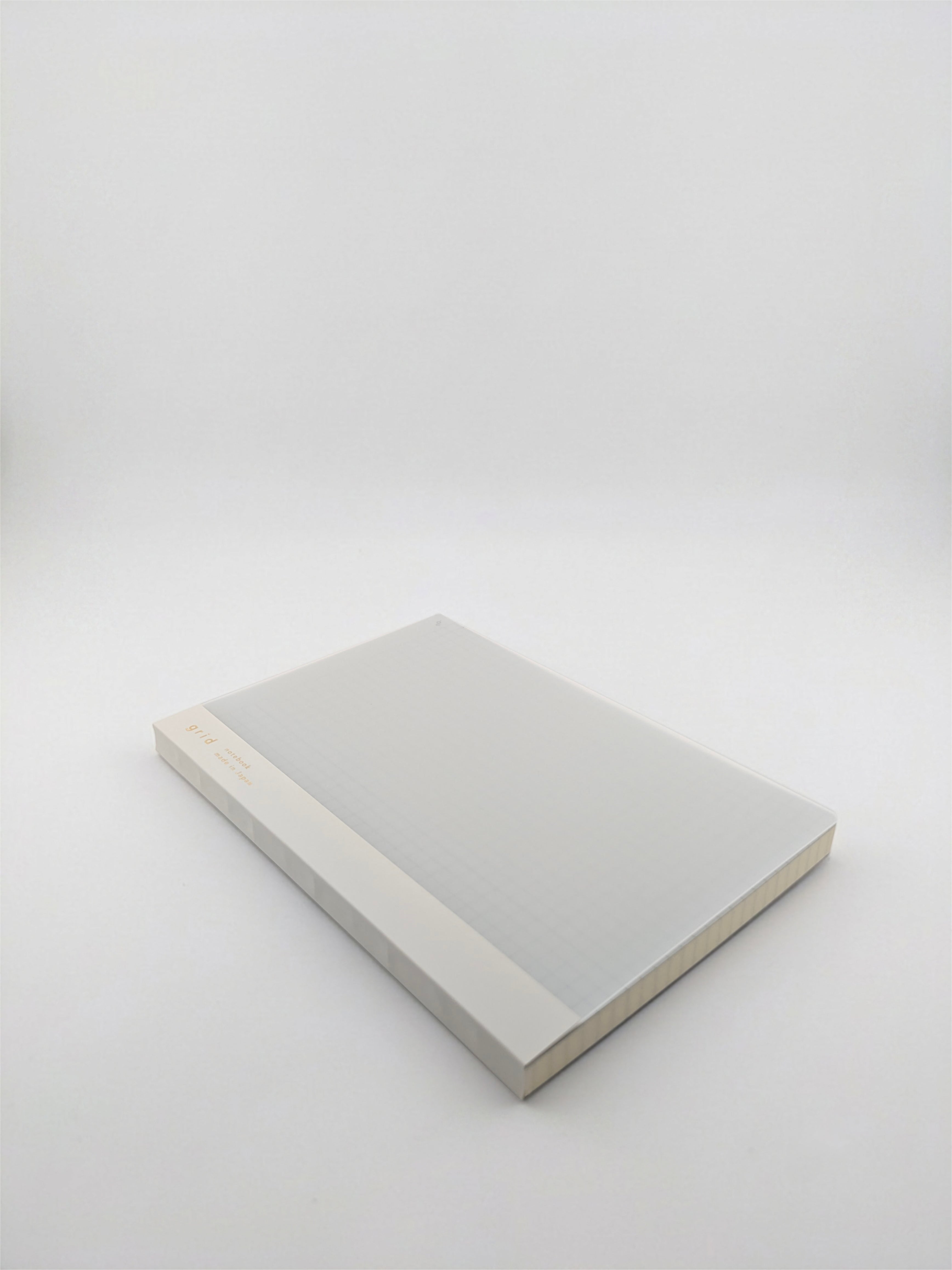A minimalist hardcover book or notebook with a light gray cover and a beige spine, photographed on a seamless light gray studio background.