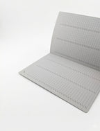 A gray grid cutting mat with printed measurement markings, shown partially unfolded on a clean white background.