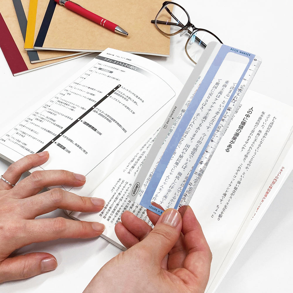 A ruler magnifying text from book on the background.