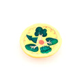 Round yellow object with green leaf-like shapes and a red center on a white background