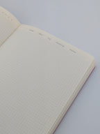An open grid notebook with cream-coloured pages, photographed on a white background