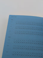 A blue graph-paper style habit tracker sheet with labeled sections for habit, daily, and monthly tracking, photographed on a plain light background.
