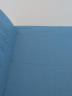 A light blue grid planner or notebook page with printed month labels and blank lines for writing, photographed against a white background.