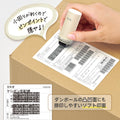 Hand holding cream white privacy stamp demonstrating the use of the stamp on carton.