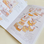 Opened book with tofu making illustration set against cream white background.