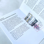 Open book with text and illustration of a building on a white surface.