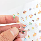 Hand holding mini food-themed stickers over white background.